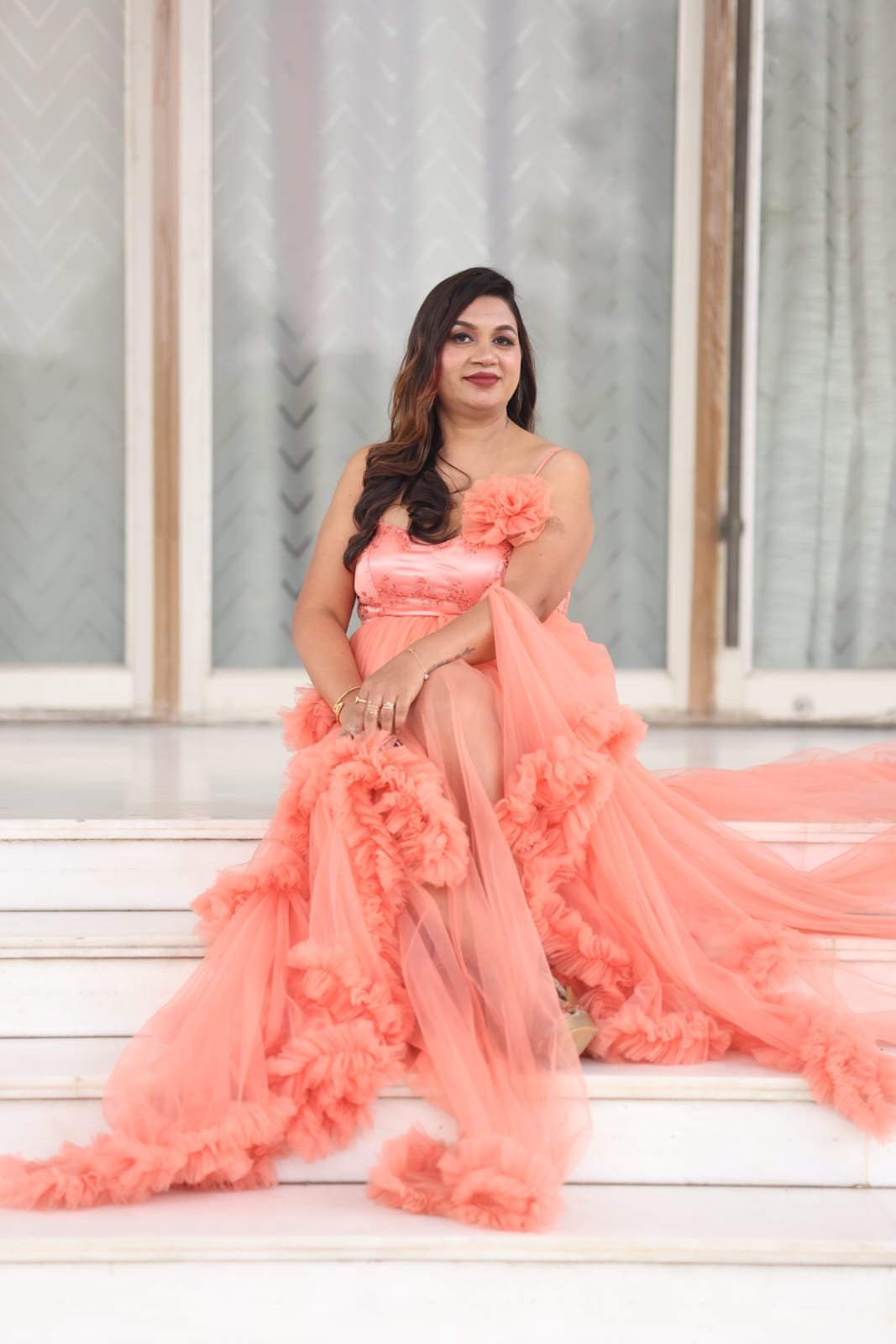 Neelam Roy in coral ruffle tulle couture gown on marble steps